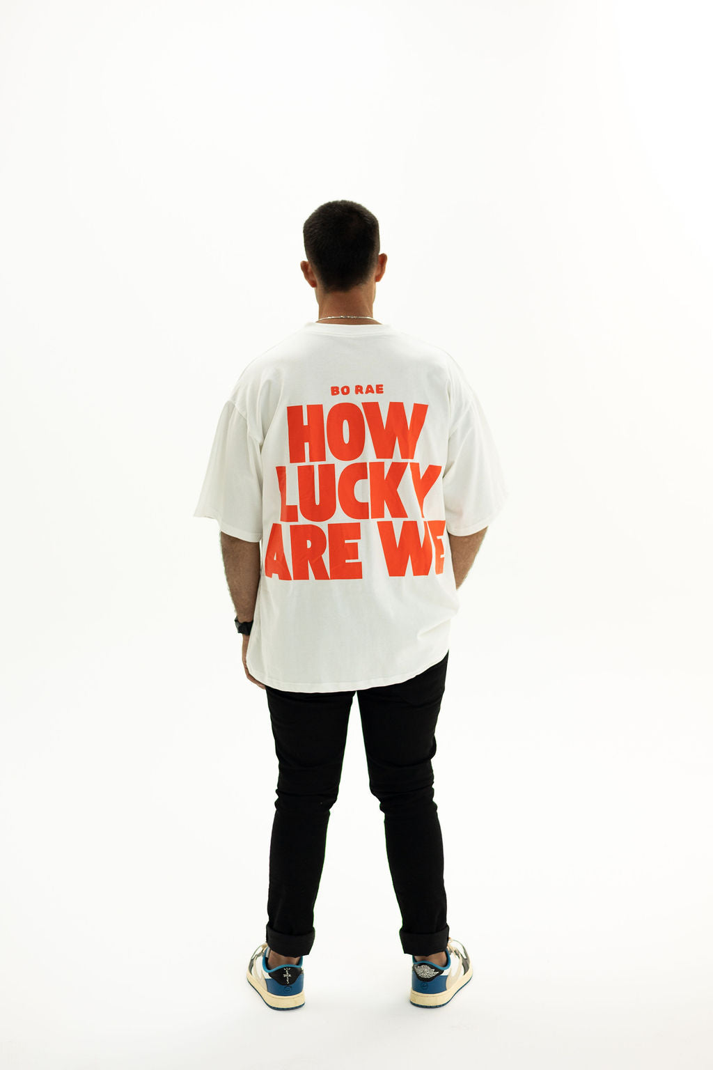 Back view of BO RAE How Lucky Are We oversized unisex adult T-shirt in white featuring large Red graphic print