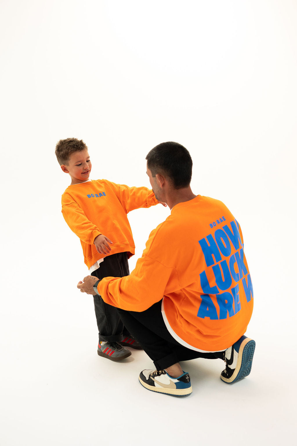 Adult and child wearing matching BO RAE How Lucky Are We oversized jumpers in orange.