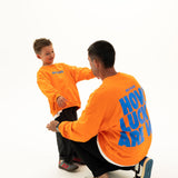 Adult and child wearing matching BO RAE How Lucky Are We oversized jumpers in orange.