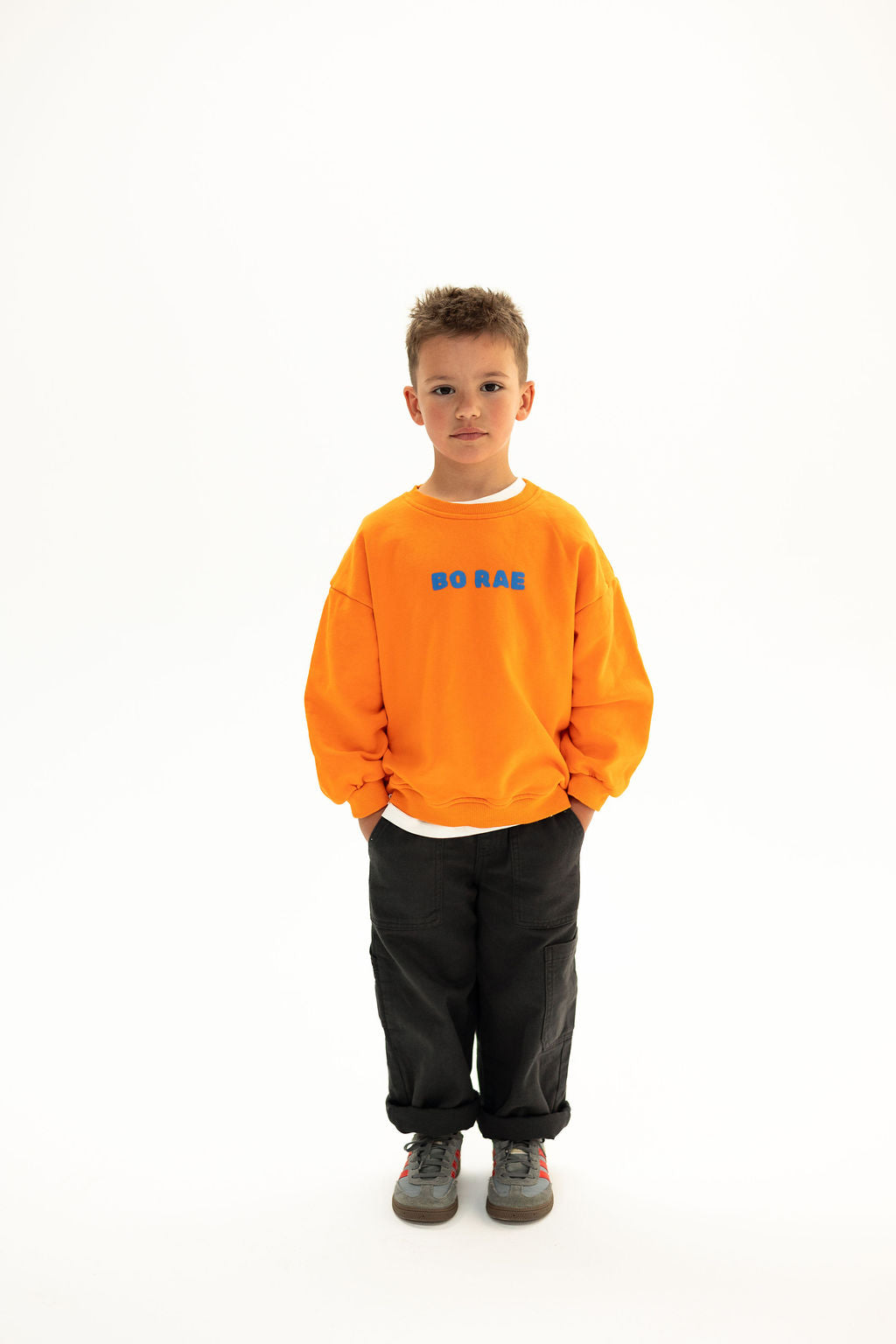 BO RAE How Lucky Are We oversized kids jumper in orange, front view with blue chest logo.