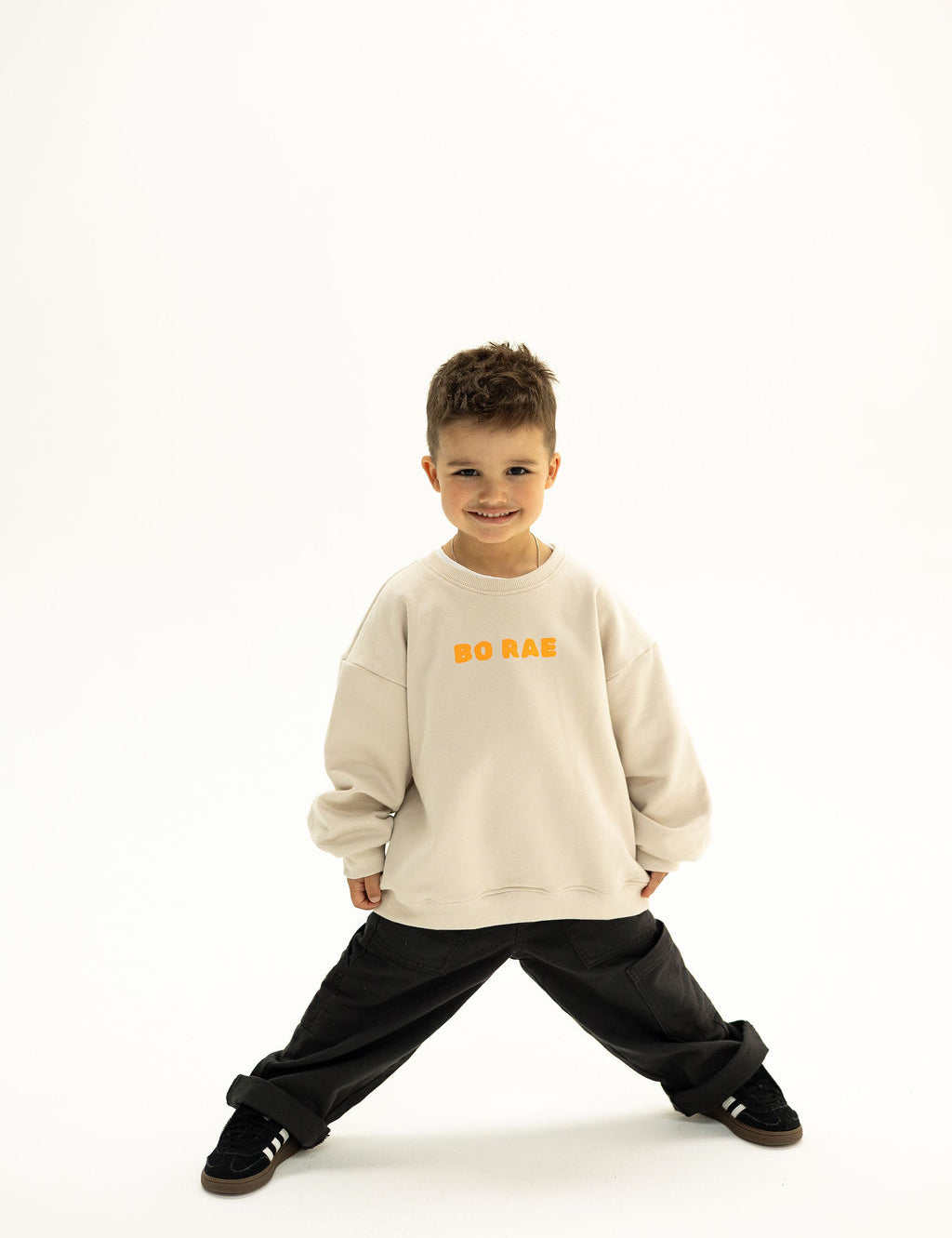 BO RAE Front view of BO RAE How Lucky Are We oversized kids jumper in Beige with orange chest logo