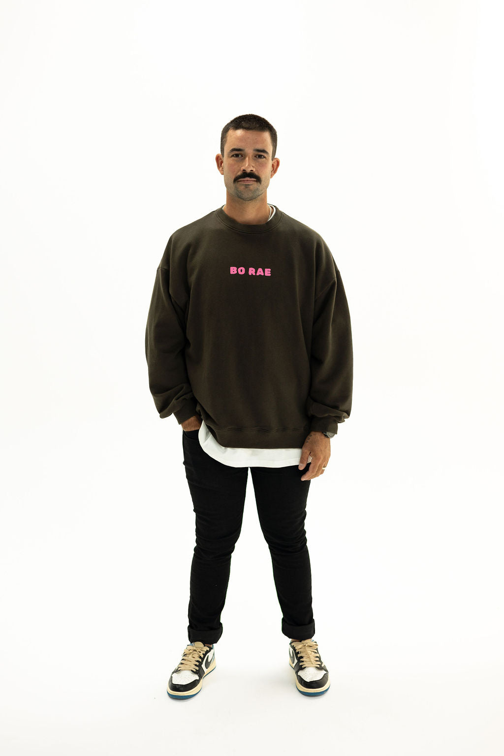 Model wearing BO RAE How Lucky Are We oversized unisex adult jumper in Khaki Slate Grey with pink chest logo