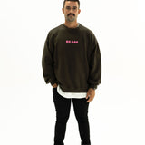 Model wearing BO RAE How Lucky Are We oversized unisex adult jumper in Khaki Slate Grey with pink chest logo