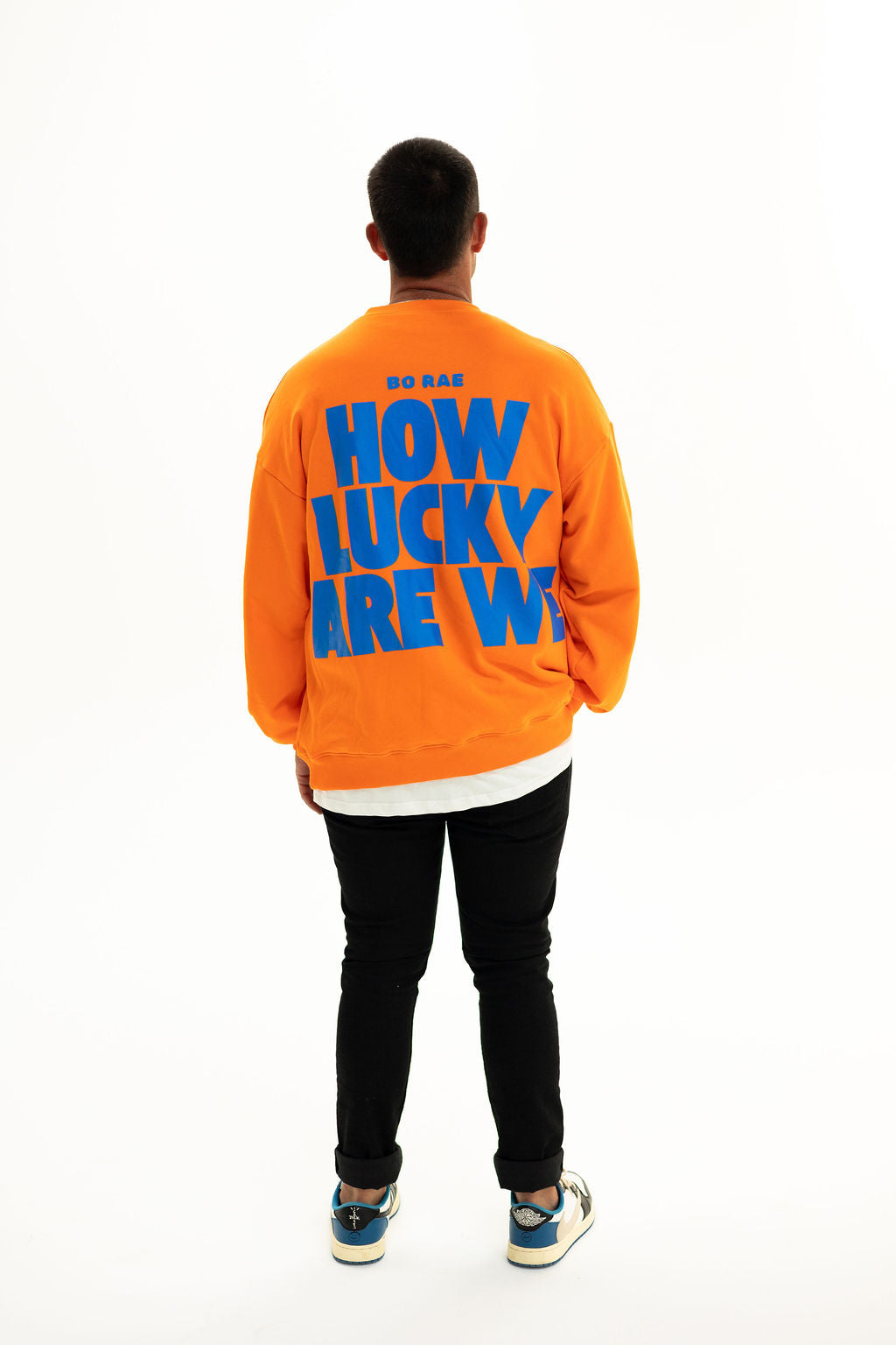 Back of BO RAE How Lucky Are We oversized unisex adult jumper in orange featuring large blue graphic print