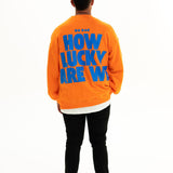 Back of BO RAE How Lucky Are We oversized unisex adult jumper in orange featuring large blue graphic print