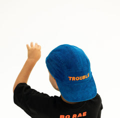 Child wearing BO RAE Trouble Hat kids corduroy camp cap in blue while facing away.