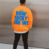 Model wearing BO RAE How Lucky Are We oversized orange adult jumper with large blue back graphic