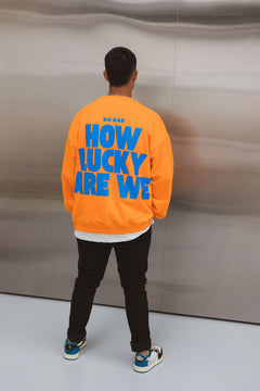Model wearing BO RAE How Lucky Are We oversized orange adult jumper with large blue back graphic