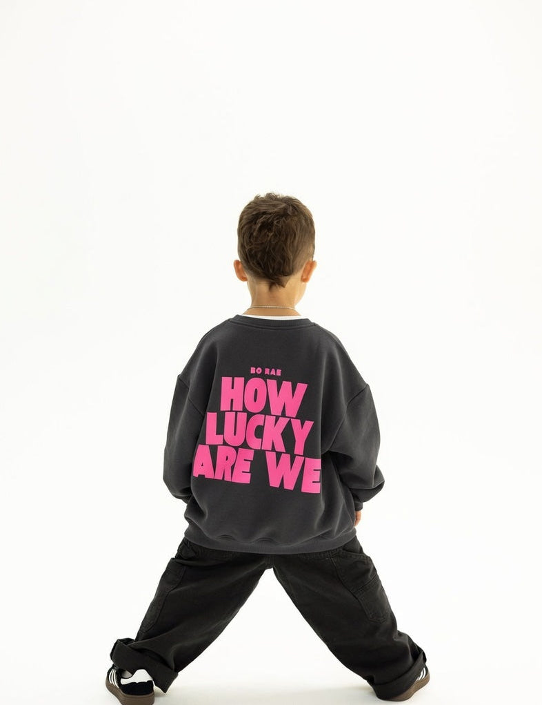 Back view of BO RAE How Lucky Are We oversized kids jumper in Khaki Slate Grey featuring large pink graphic print.