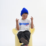 BO RAE How Lucky Are We oversized kids T-shirt in white, child sitting on chair wearing blue beanie.