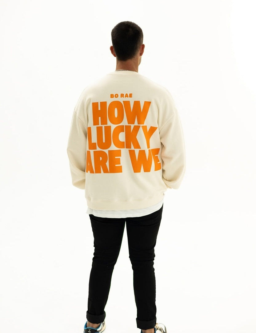Back view of BO RAE How Lucky Are We oversized unisex adult jumper in Beige featuring large orange graphic print